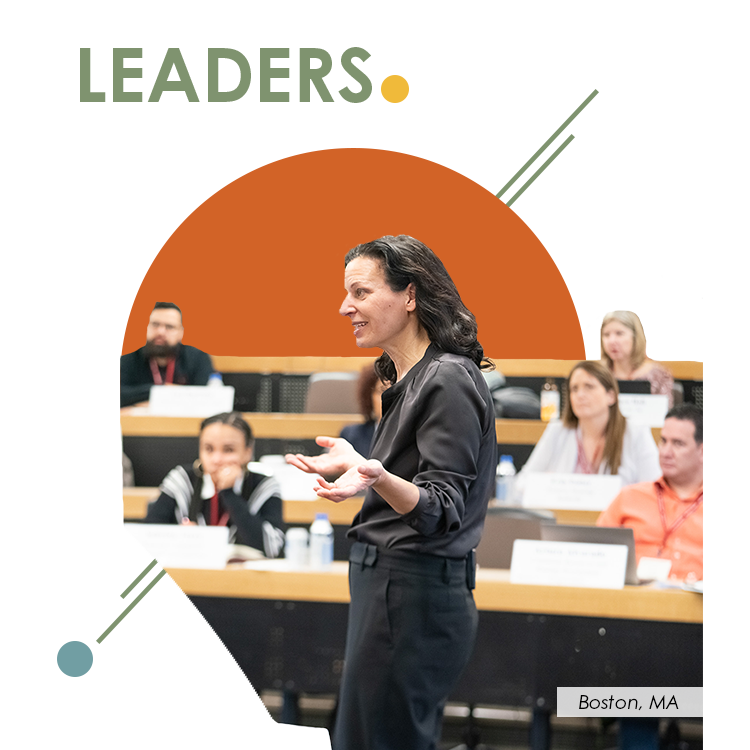leaders-annual-report-NW A woman speaks passionately in front of a classroom of adult learners seated in tiered rows. She gestures with open hands, engaging the diverse group of participants who appear attentive and focused. The word “LEADERS” is overlaid on the image with bold, modern typography, along with the location label “Boston, MA.